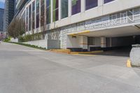 the view of a parking garage in front of a high rise building on an empty street