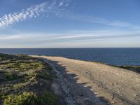 a view of a large body of water with a path leading to the beach and sky