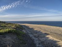 a view of a large body of water with a path leading to the beach and sky