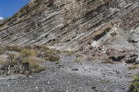 a view of an area with rocks and scrubs, on the side of a large mountain side