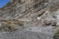 a view of an area with rocks and scrubs, on the side of a large mountain side