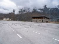 a view from the top of an empty parking lot with a small wooden cabin and two road markings