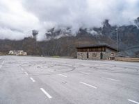 a view from the top of an empty parking lot with a small wooden cabin and two road markings