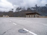 a view from the top of an empty parking lot with a small wooden cabin and two road markings