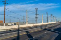 a view of some utility poles and wires and an empty road and a traffic light