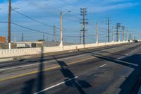 a view of some utility poles and wires and an empty road and a traffic light