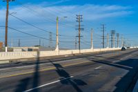 a view of some utility poles and wires and an empty road and a traffic light