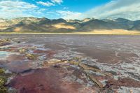 a view of the vast, pink colored ground at the bottom of a desert plain