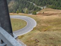 view down from a helicopter of the winding road going uphill in the mountains with a mountain range