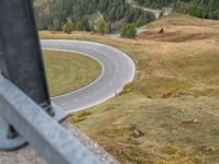 view down from a helicopter of the winding road going uphill in the mountains with a mountain range