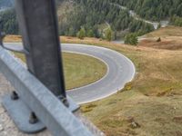 view down from a helicopter of the winding road going uphill in the mountains with a mountain range