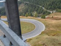 view down from a helicopter of the winding road going uphill in the mountains with a mountain range