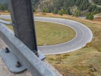 view down from a helicopter of the winding road going uphill in the mountains with a mountain range