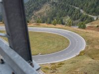 view down from a helicopter of the winding road going uphill in the mountains with a mountain range