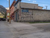 a red fire hydrant sitting in front of an old store window and building next to an open air field