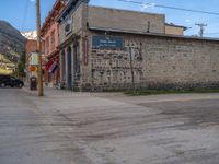 a red fire hydrant sitting in front of an old store window and building next to an open air field