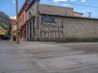 a red fire hydrant sitting in front of an old store window and building next to an open air field