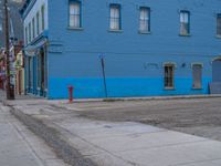 a red fire hydrant sitting in front of an old store window and building next to an open air field