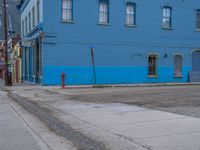 a red fire hydrant sitting in front of an old store window and building next to an open air field