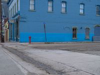 a red fire hydrant sitting in front of an old store window and building next to an open air field