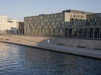 the people are walking along the side of the canal in the water near some buildings