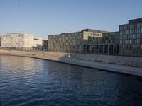 the people are walking along the side of the canal in the water near some buildings