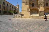 a person is walking down the street with an umbrella on an empty brick pavement in a stone courtyard