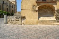 a person is walking down the street with an umbrella on an empty brick pavement in a stone courtyard