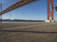 a person walking towards the bay while standing under a bridge over water and with mountains in the distance