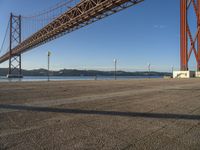 a person walking towards the bay while standing under a bridge over water and with mountains in the distance