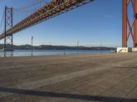 a person walking towards the bay while standing under a bridge over water and with mountains in the distance