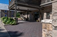 a walkway leading to the front door of a home with some landscaping around it, and two balconies in the background