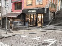 street with stores and signs and stairs up to them, and a pedestrian on the sidewalk