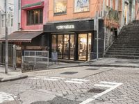 street with stores and signs and stairs up to them, and a pedestrian on the sidewalk