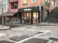 street with stores and signs and stairs up to them, and a pedestrian on the sidewalk