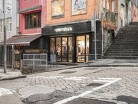 street with stores and signs and stairs up to them, and a pedestrian on the sidewalk