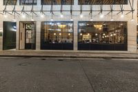 an empty street next to a restaurant with the doors opened at night time in urban city