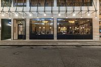 an empty street next to a restaurant with the doors opened at night time in urban city