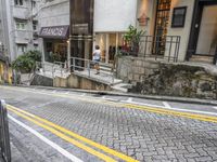 a city street has an empty white bus stop sign in the middle of it and a stone road