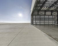 a large warehouse with a large empty wing on a sunny day on an airport tarmac