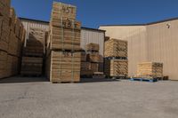 many pallets are stacked in the corner near a building in a warehouse area with luggage