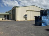 a large warehouse with some crates on the side of it and a truck next to it