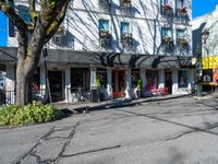 an empty street in front of small businesses along with tall windows and trees surrounding it