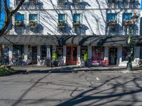 there is a bicycle parked in the street outside the storefront of this building as pedestrians pass