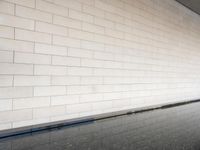 a water feature reflecting light and sky in the center of a white brick wall with a black edge