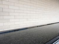 a water feature reflecting light and sky in the center of a white brick wall with a black edge