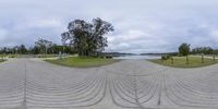 there is a street scene looking at a water and trees in the background in this view from 360 point perspective