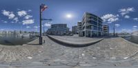 a fish - eye lens of an apartment complex by the water with sailboats in the background