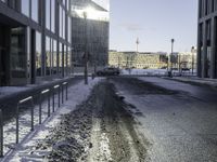 a car parked in the middle of the road near large buildings with snow on them