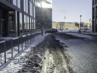 a car parked in the middle of the road near large buildings with snow on them